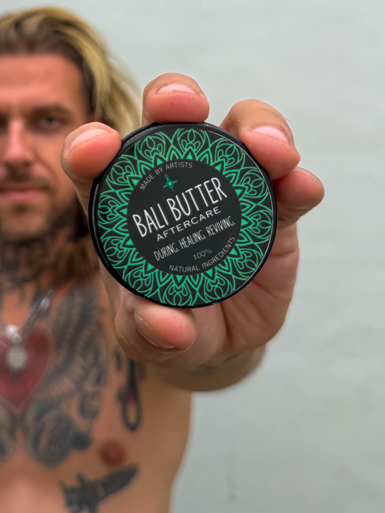 Tattoo artist holding a tin of Bali Butter Aftercare